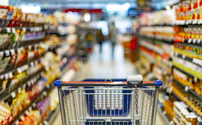 A shopping cart next to a store shelf in a supermarket